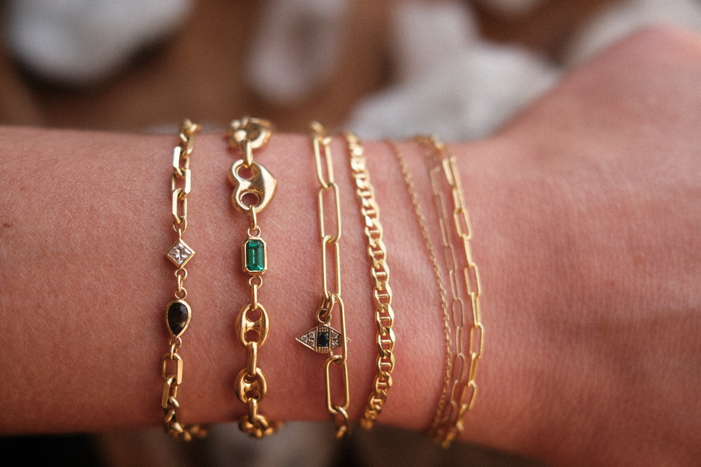 7 different types of 14K solid gold chain bracelets with and without gemstone modeling the various ways a love saro custom bracelet can come to life.