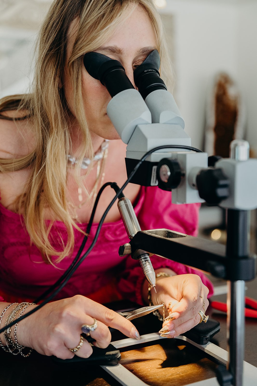 Love Saro jewelry designer hand-welding a permanent bracelet under a microscope at the Denver studio