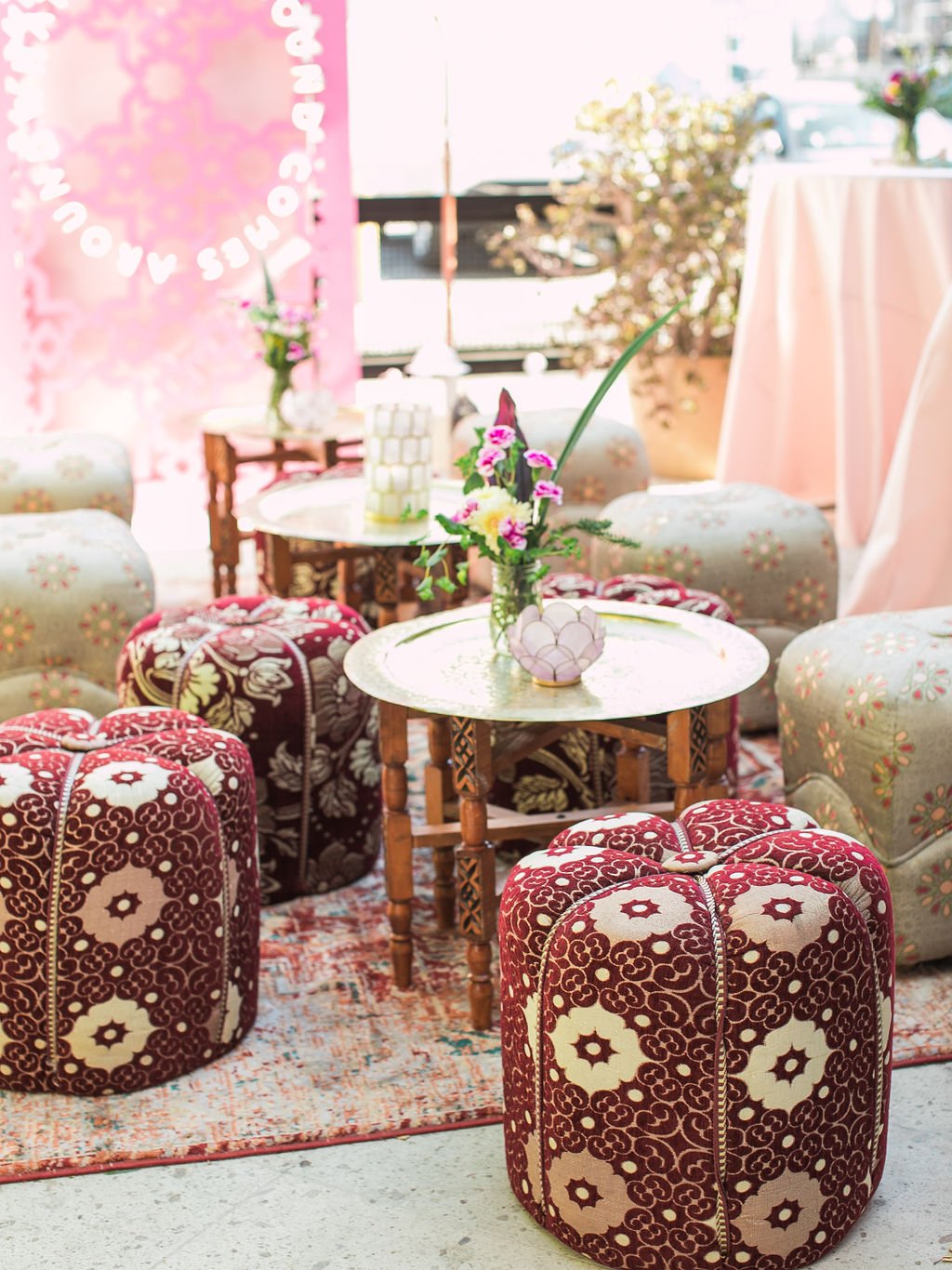 Chic and inviting lounge area inside Love Saro’s Melrose Place studio, featuring vintage floral ottomans and custom pink decor for luxury permanent jewelry appointments