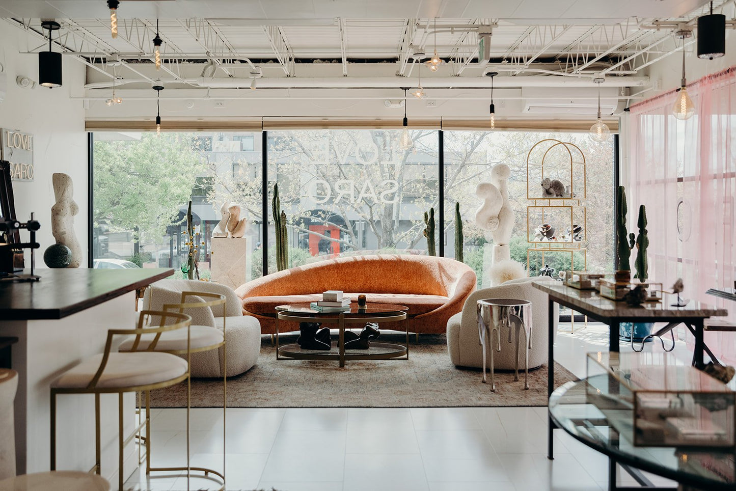 Love Saro’s Denver studio lounge area with plush seating and modern sculpture, designed for luxury permanent jewelry consultations