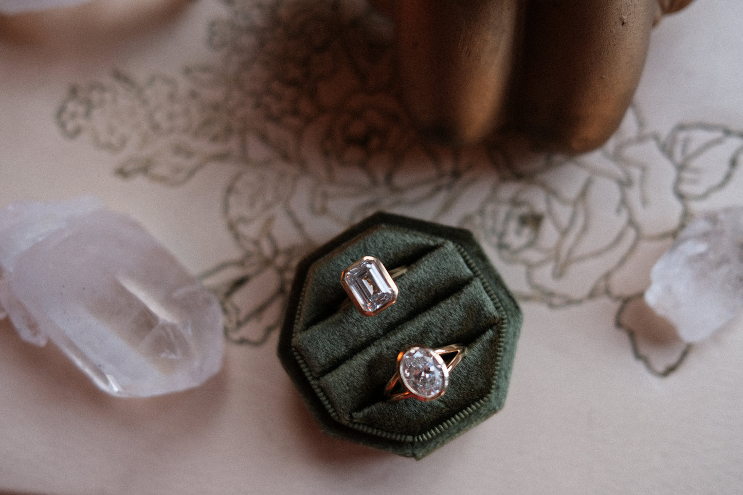 Two rings in a green velvet box on a floral-patterned surface