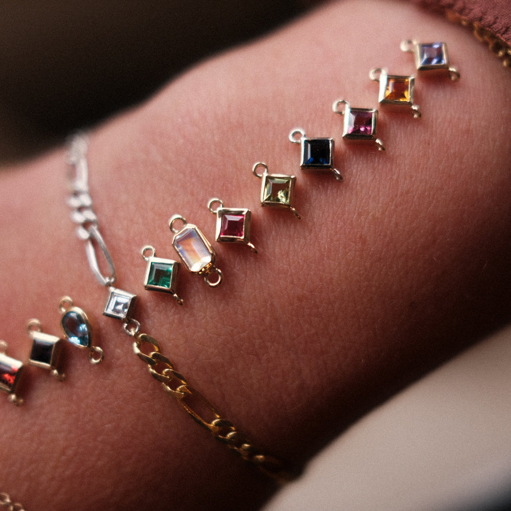 The birthstone gemstones laid out on a wrist with Aprils already added to a custom bracelet