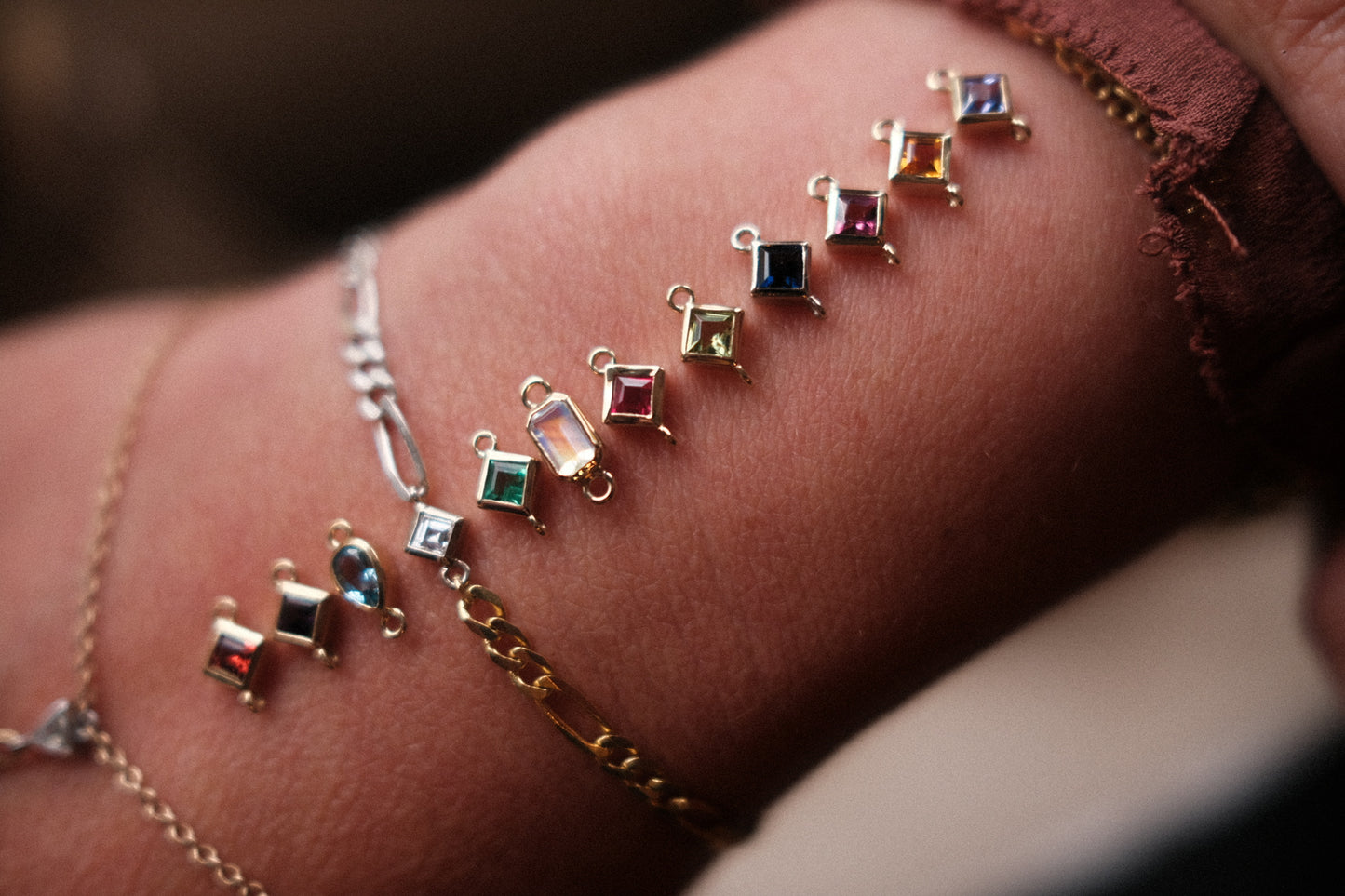The birthstone gemstones laid out on a wrist with Aprils already added to a custom bracelet