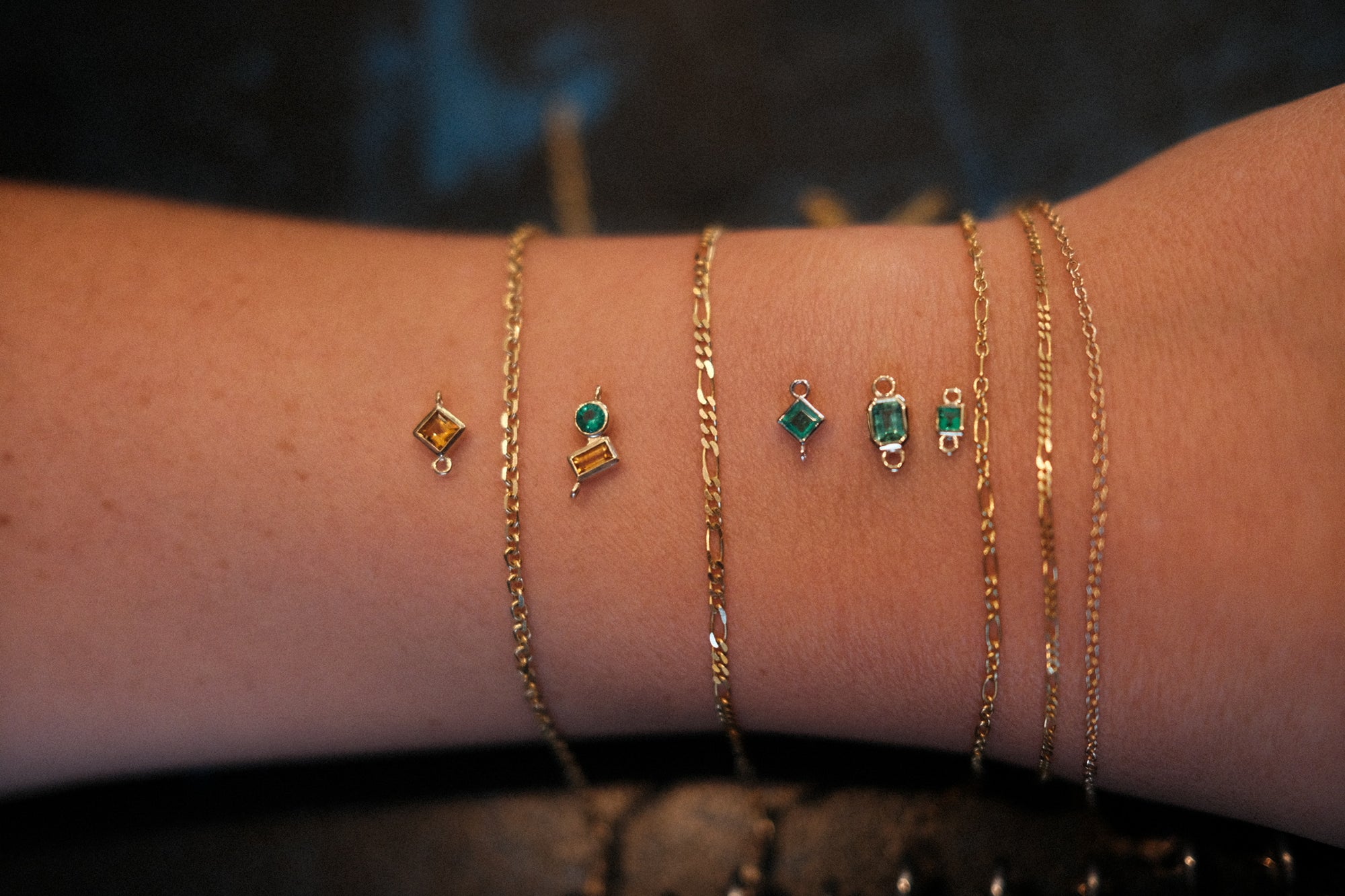 Custom permanent bracelets in 14K gold with birthstone charms, designed at Love Saro’s Boulder studio.