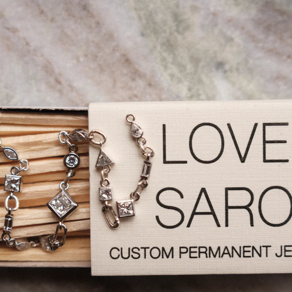 white diamond tennis bracelet luxury permanent jewelry displayed on a love saro matchbox