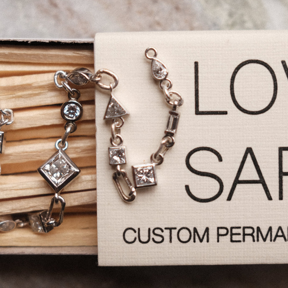 mixed shaped tennis bracelet with white diamonds displayed on a love saro matchbox